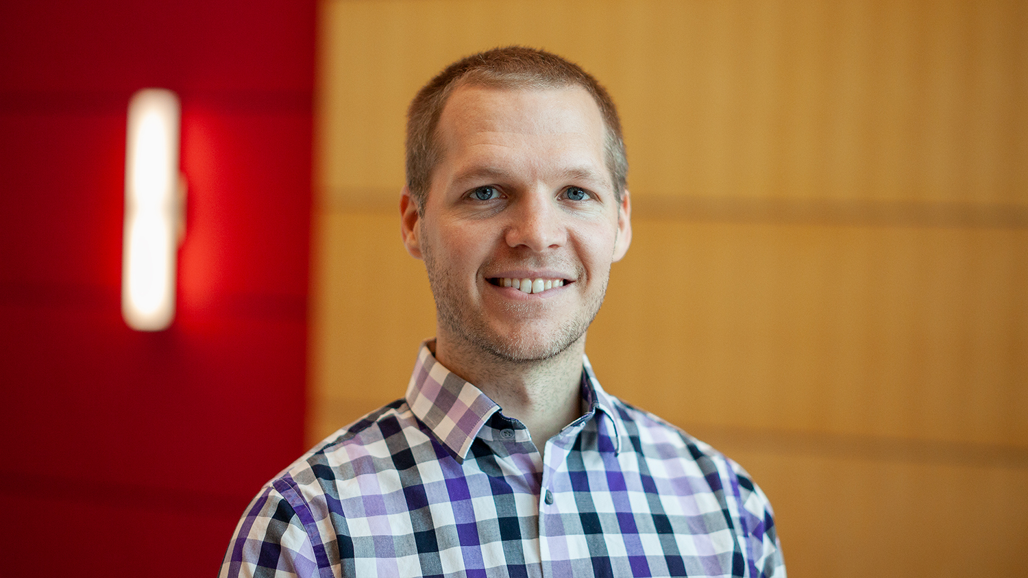 Justin Post smiling for a headshot in the CTI lobby.