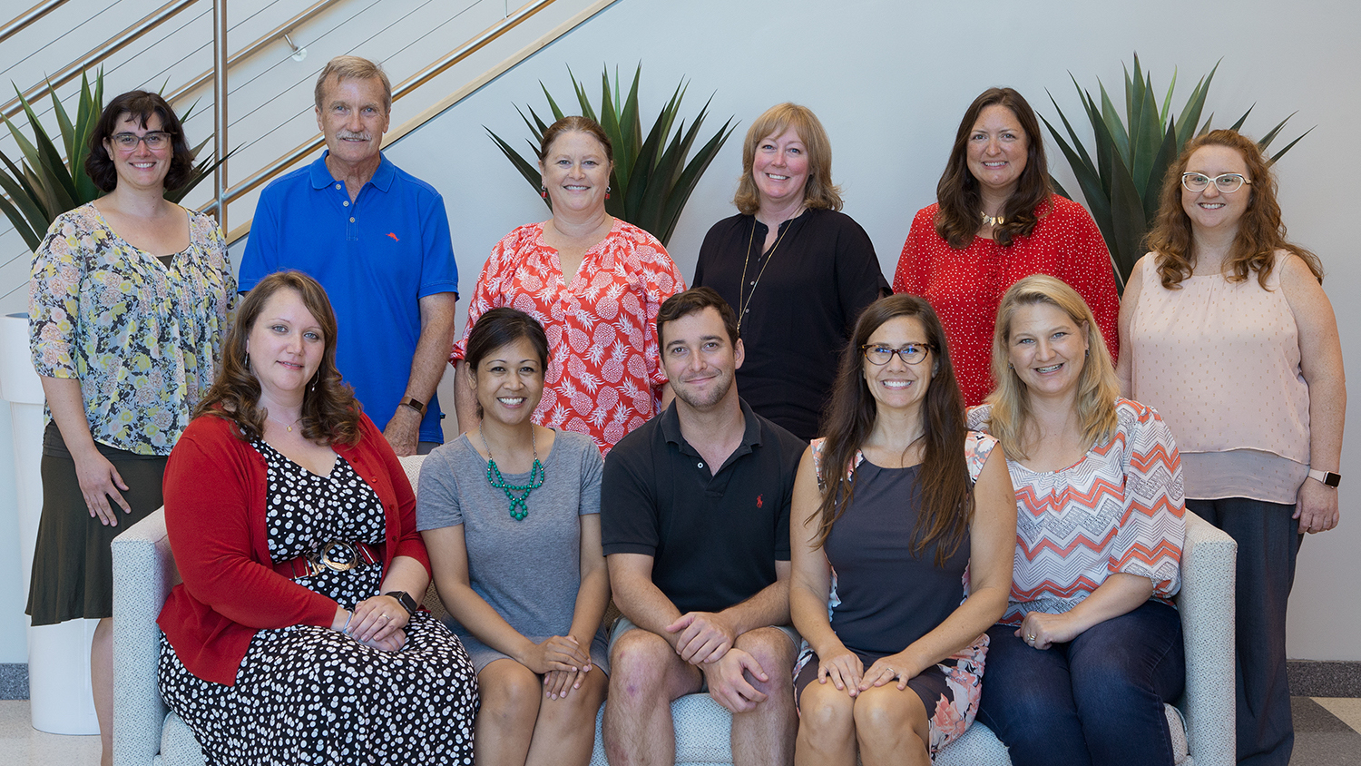 Photo of OCIP team in the CTI lobby. Back row is standing behind the front row who are seated on a couch. Back row, left to right: Molly Fenn, David Shew, Leigh Shamblin, Christine Cranford, Angie Smith, Kim Allen. Front row, left to right: Bethany Smith, Arelene Mendoza-Moran, Christopher Beeson, Bethanne Tobey, Rebecca Sanchez. Photo by Katie Harris.