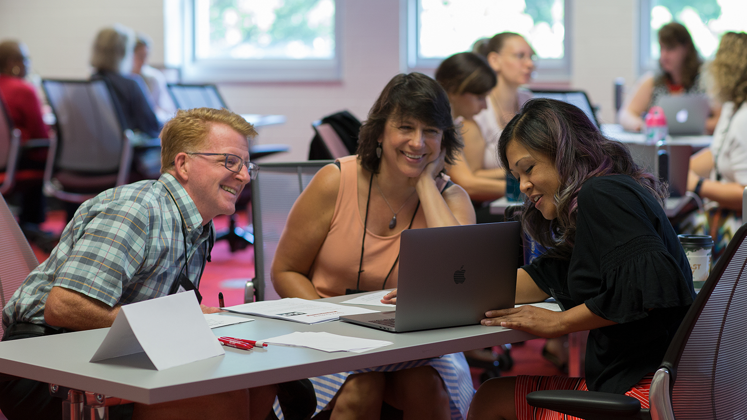 Arlene Mendoza-Moran (right) works with faculty at the 2018 Summer Shorts in Instructional Technologies program. Mendoza-Moran and faculty are working on a laptop at a desk.