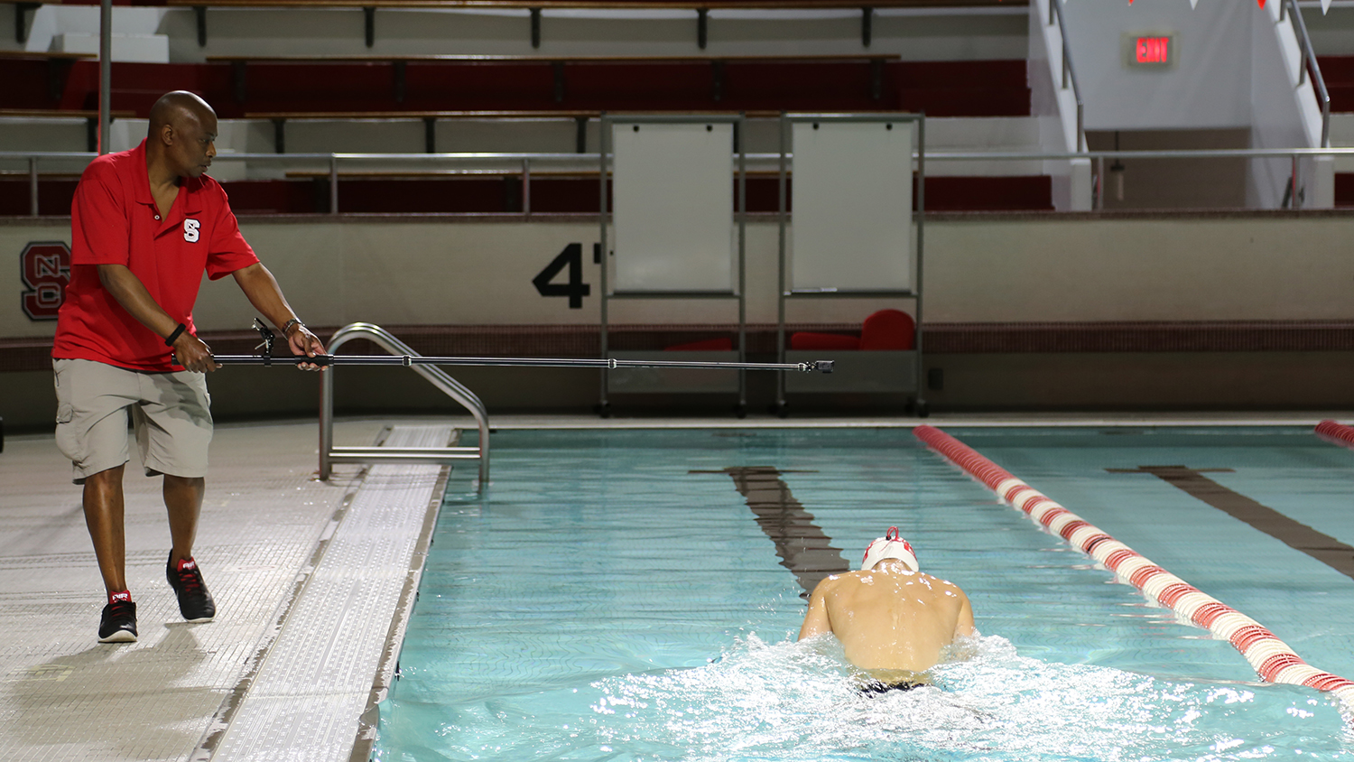Robinson holds an extended camera to record a swimmer from above in the Aquatic Center.