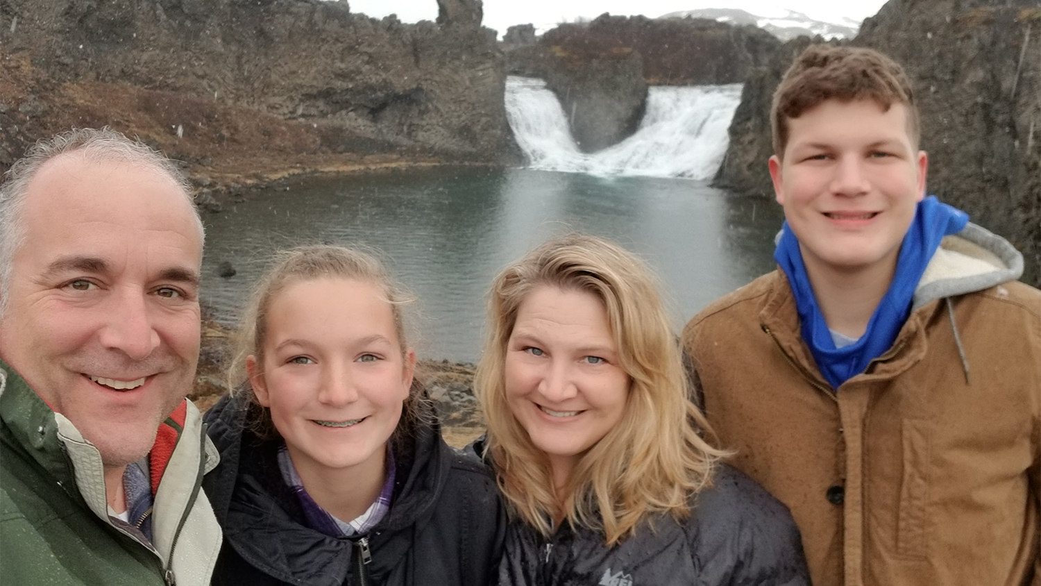 Sanchez and her husband, daughter, and son in front of rocky waterfalls.