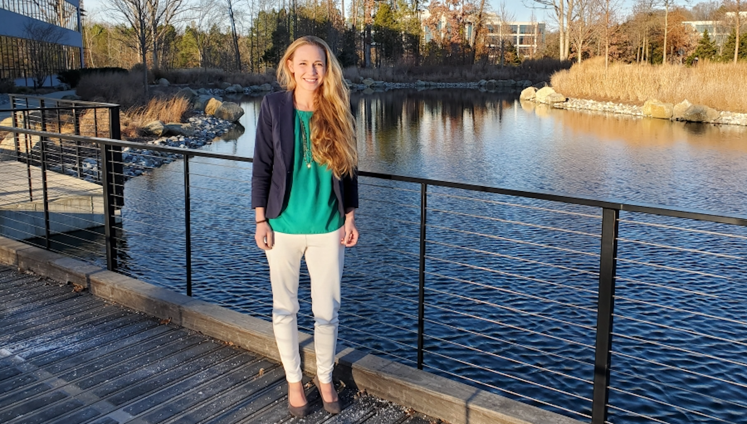 Chelsea ross smiling posed in front of a pond and buildings.