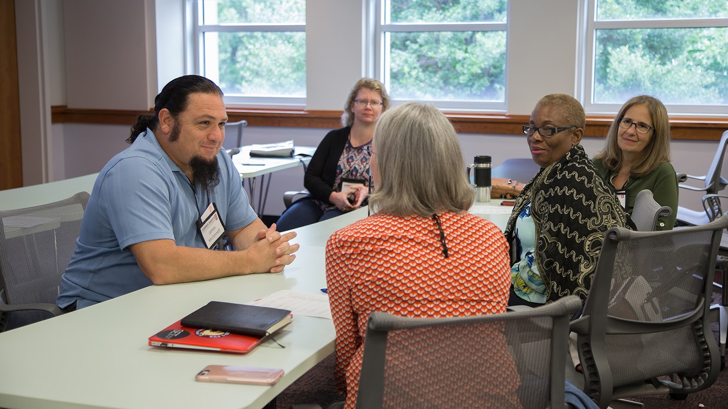 James McConnell sits at a large desk talking with a group of faculty members.