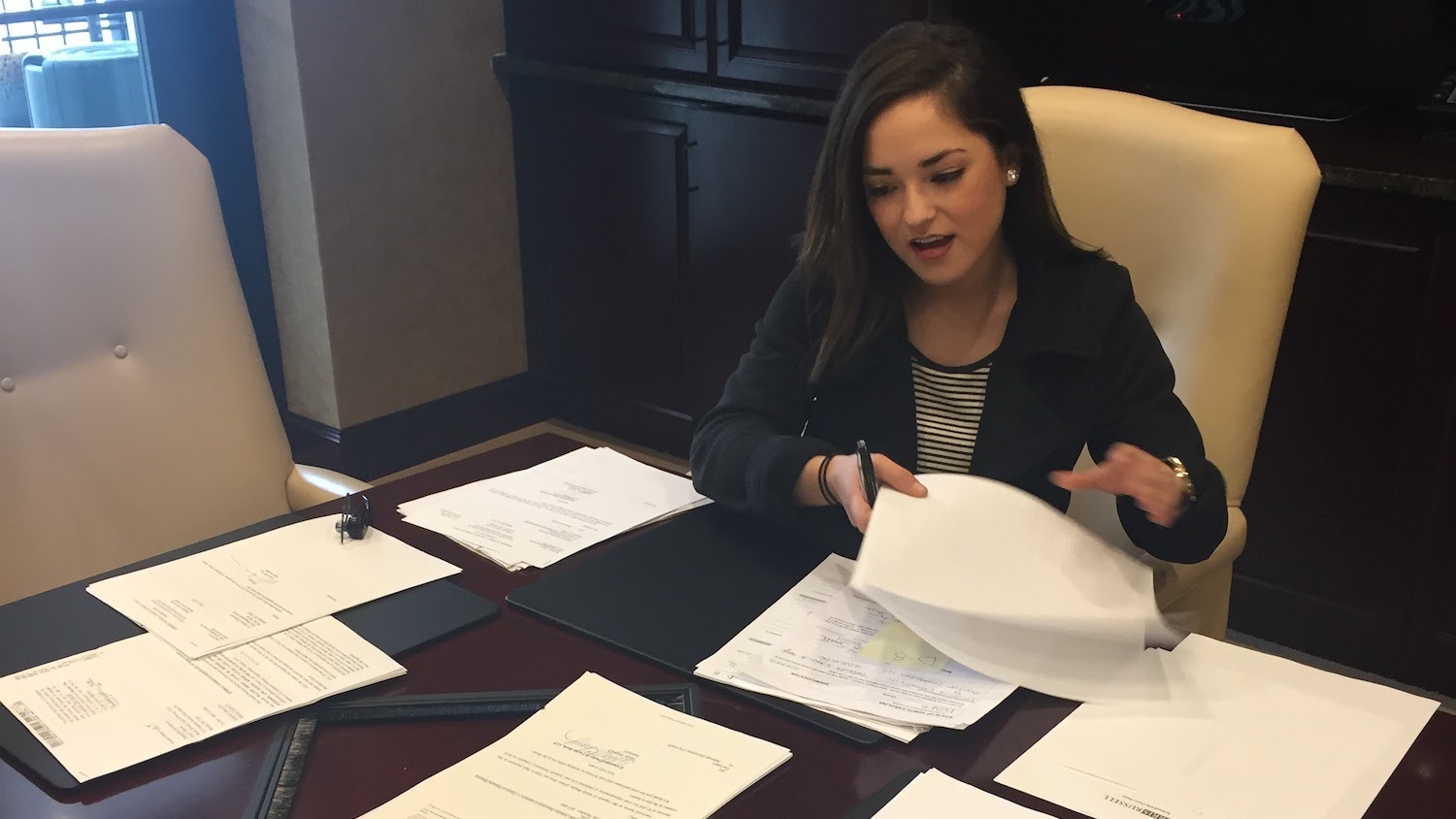 Jessica sits at a conference table working on paperwork