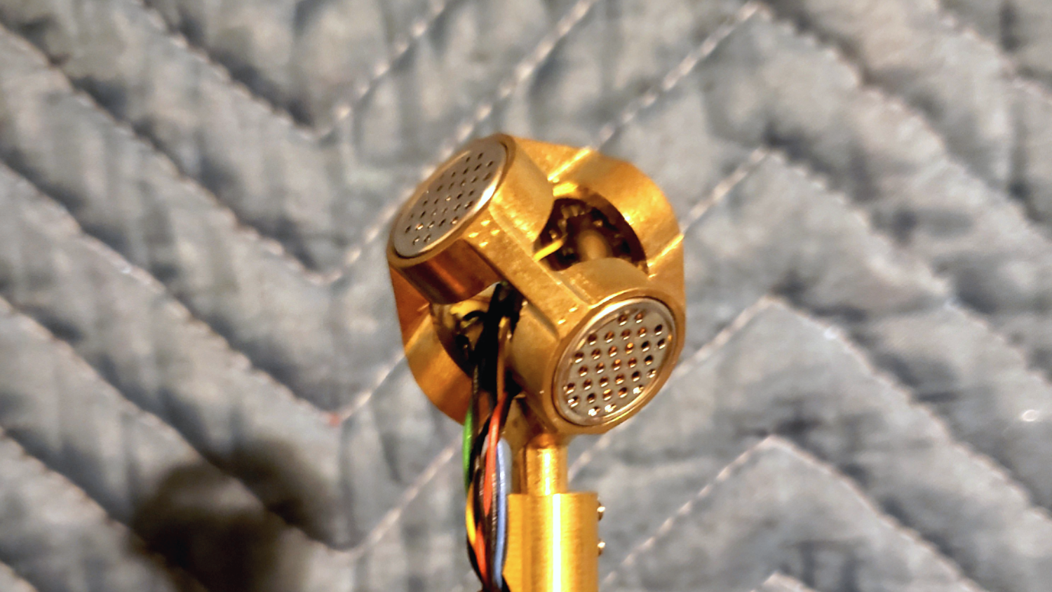 Close up of a microphone with the cover off. Mic is gold and shows the array.