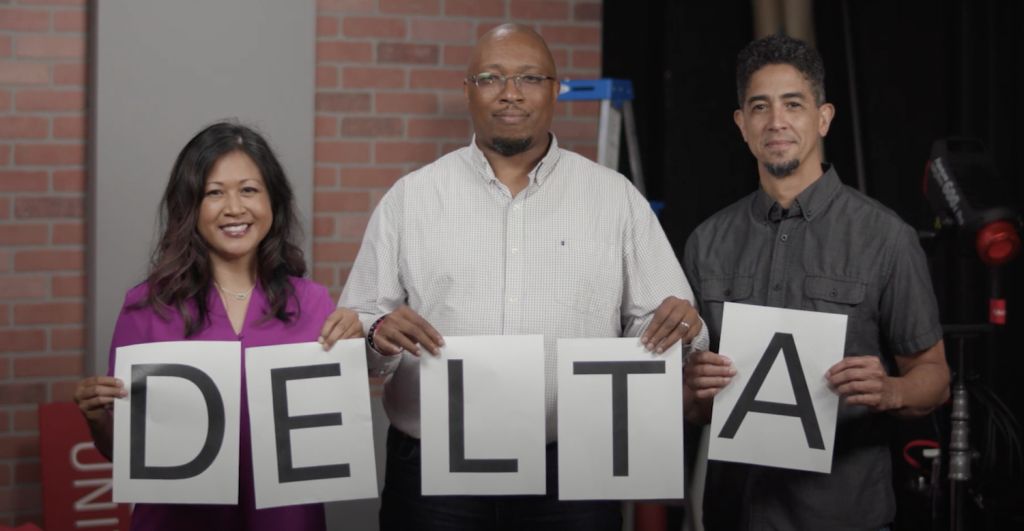 DELTA Staff members holding up cards spelling out DELTA