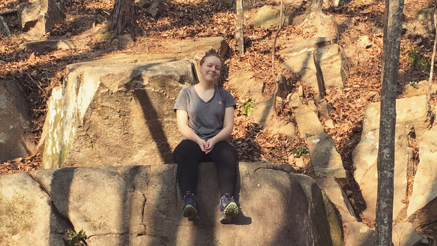 photo of Katie Richardson sitting on a rock at William B. Umstead State Park.