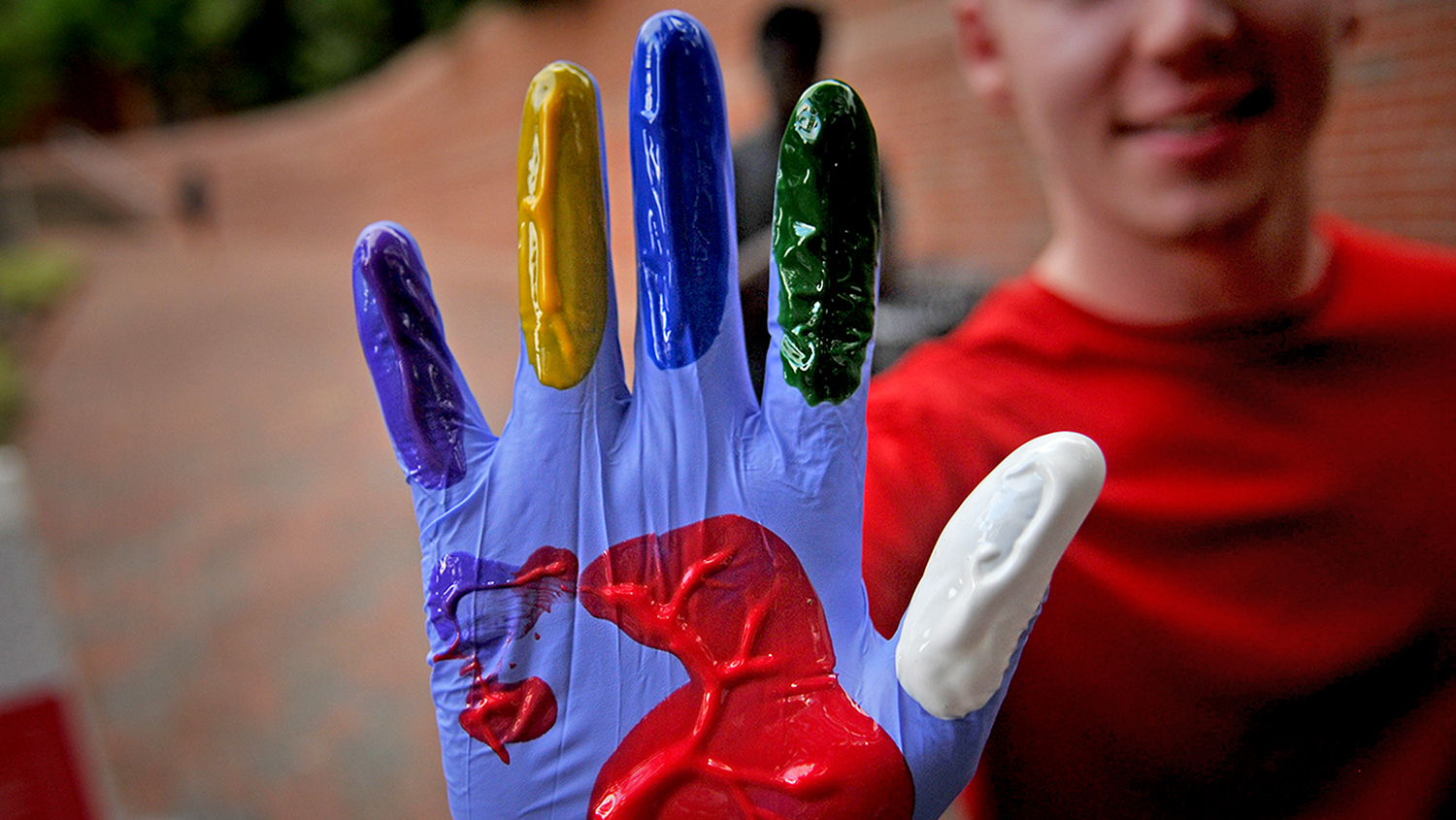 Student shows his diverse color selection before adding his hand print to the Free Expression Tunnel during Respect The Pack.