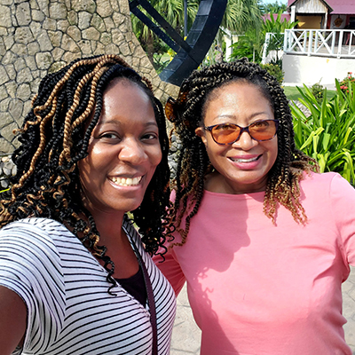 Jessica White with her aunt, Evelyn Fluellen, standing outside in a garden in Montego Bay, Jamaica, in a 2022 visit celebrating White's birthday.