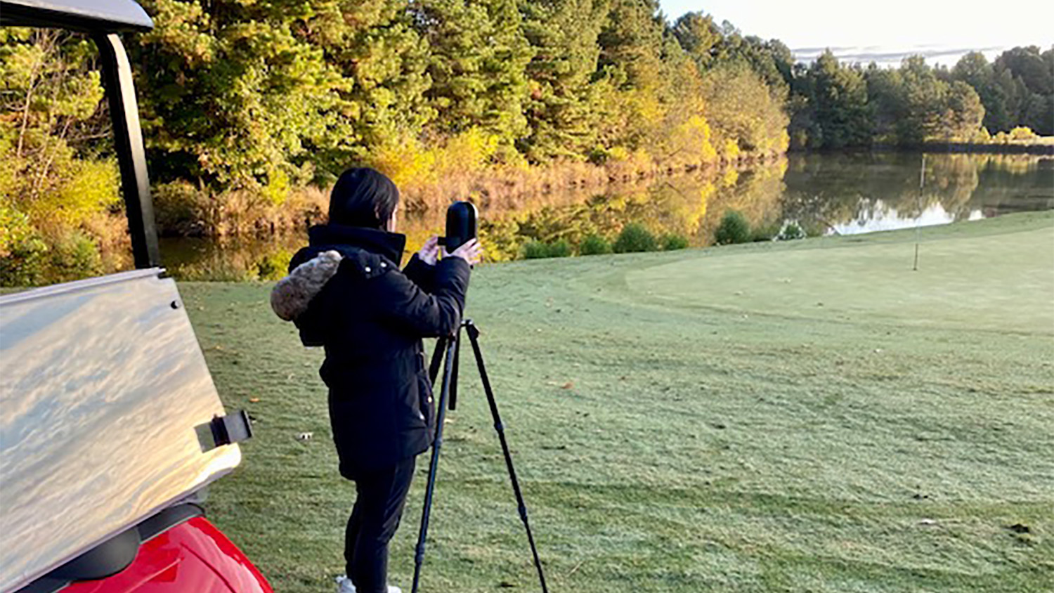 Multimedia Specialist Téa Blumer stands on a golf course and positions a Matterport camera to capture spatial scans