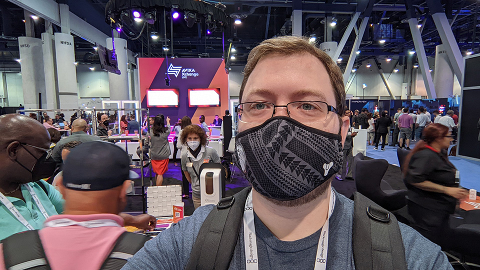 man wearing a mask standing on a convention show floor