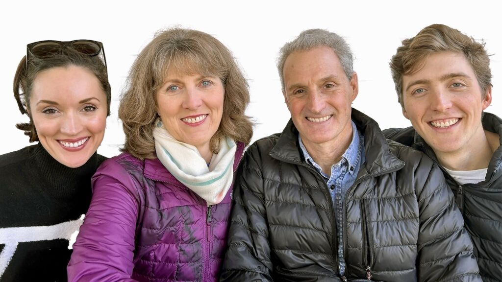 Four white adults posed in cold weather gear and smiling at the camera