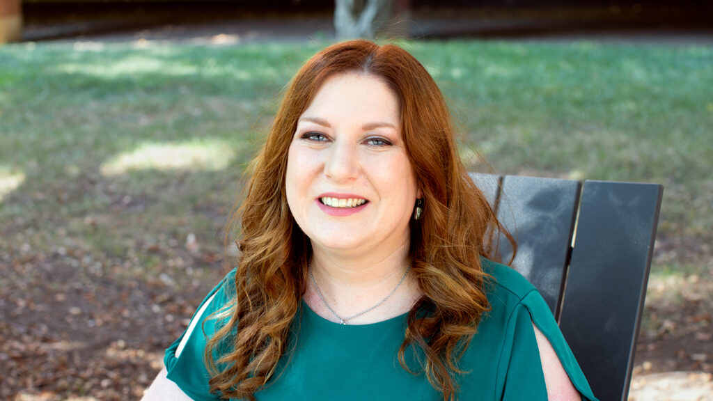 headshot of Megan Lupek, assistant teaching professor at NC State, sitting in a chair outside