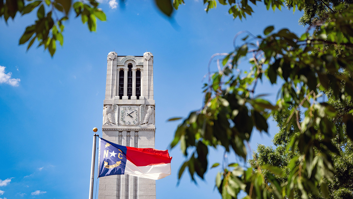 NC State Bell tower and North Carolina flag.