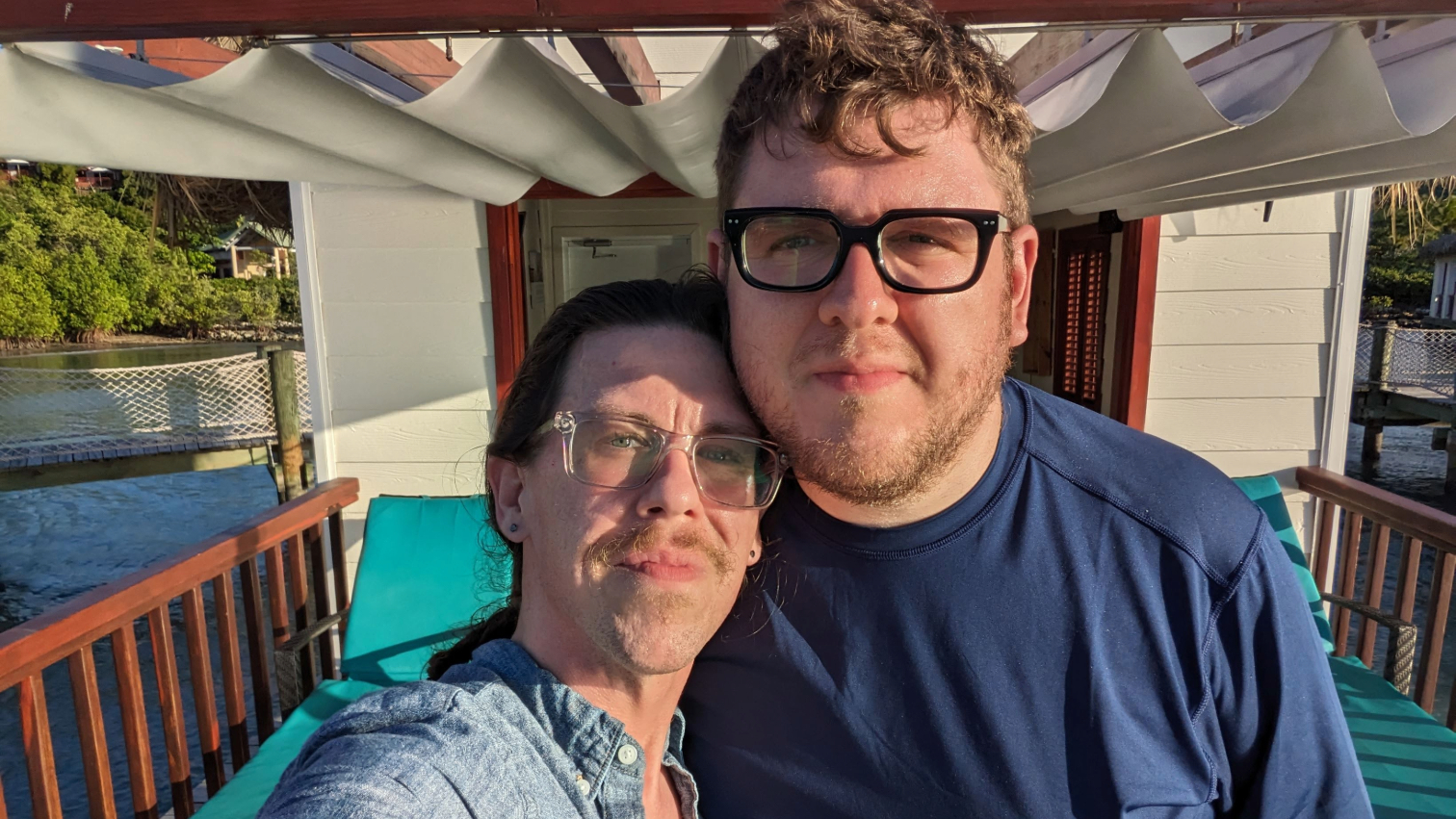 Two men pose in an outdoor cabana