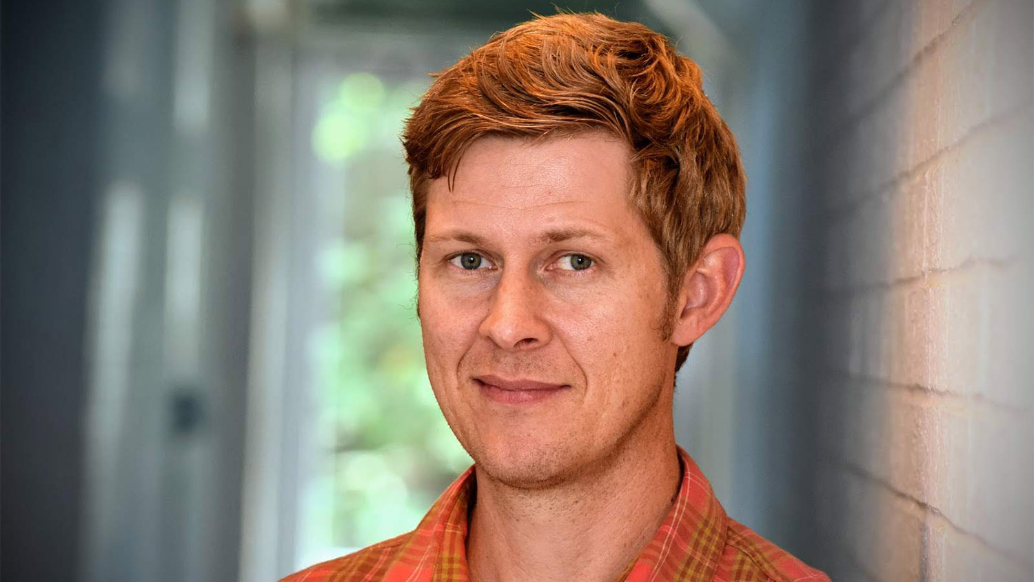 A headshot of a man in an orange shirt