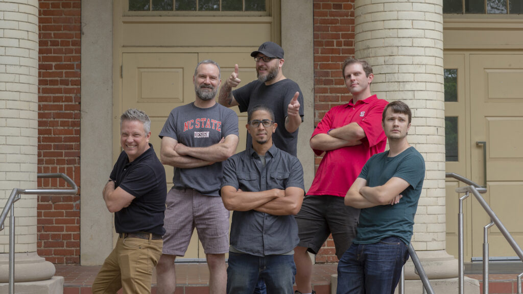 A group of men posing in front of a building