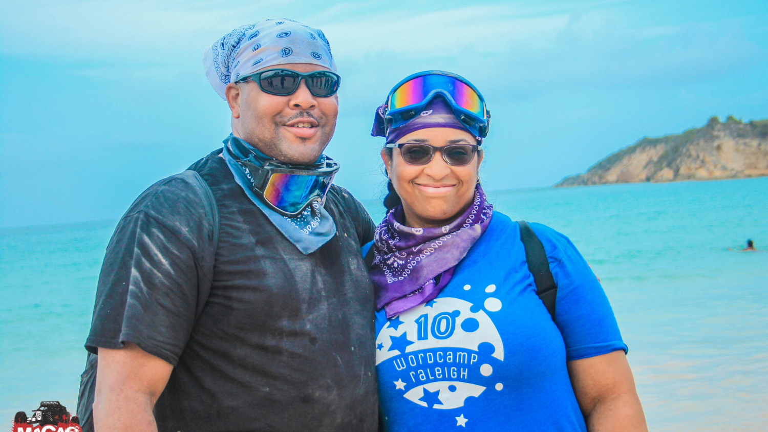 A couple posing along a coastline with mountains in the distance